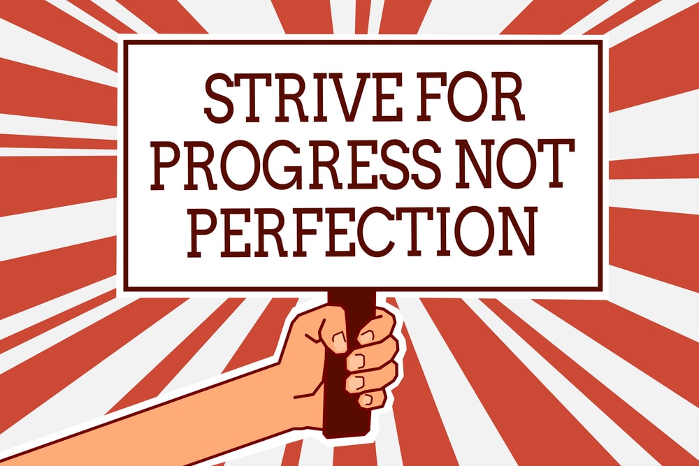 cartoon drawing of someone holding a sign saying strive for progress, not perfection
