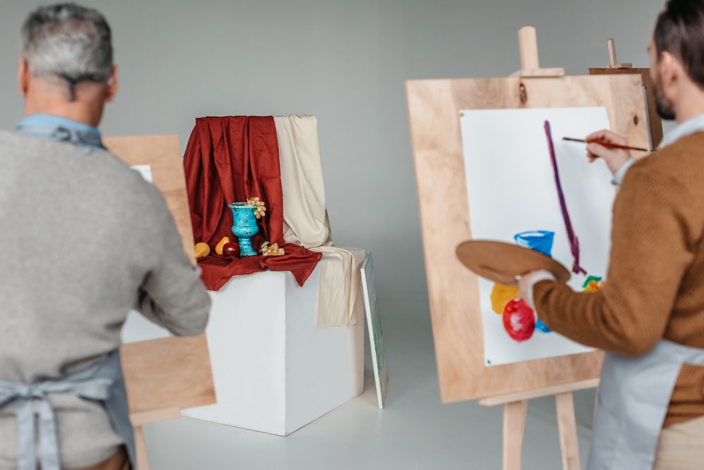 two man painting still life on an art class
