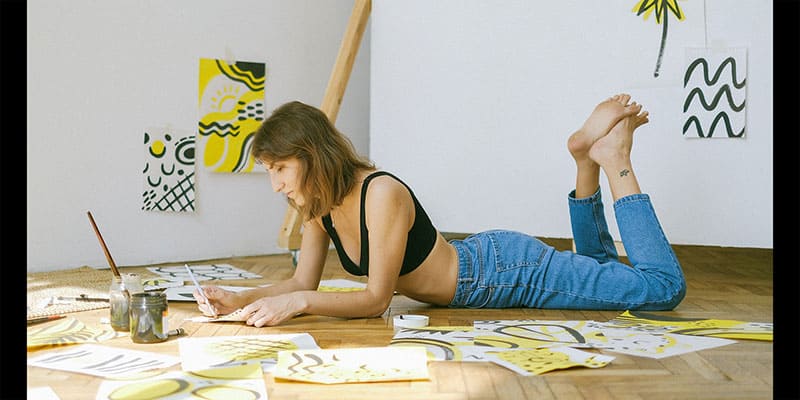 photo of a girl lying down drawing and painting